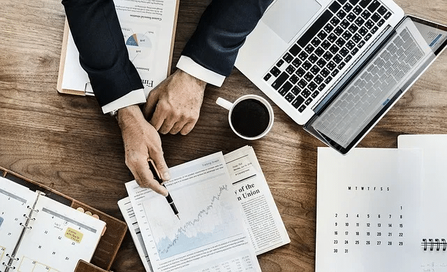 Man working on office desk pointing to a business graph